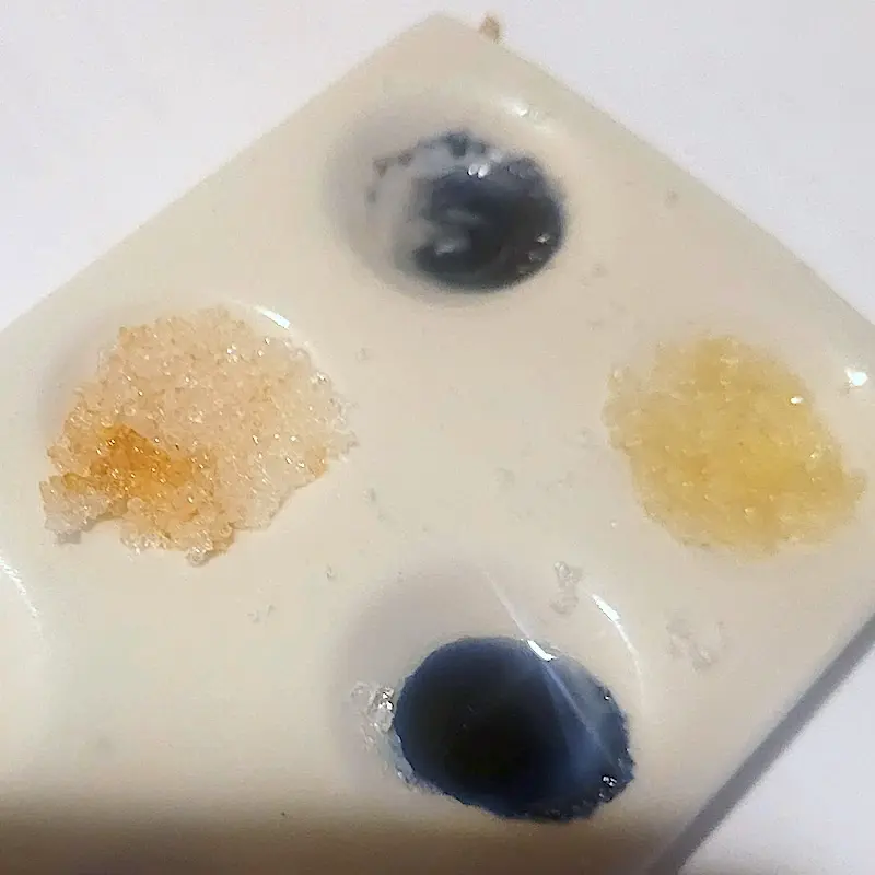 Una piastrina di ceramica a quattro pozzetti con cristalli di metanfetamina: due pozzetti sono diventati blu scuro con il reagente Simon's, negli altri due i cristalli sono arancioni e giallo pallido dopo il Marquis